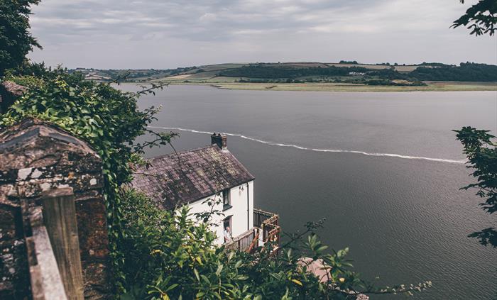 Looking down at the Boathouse from the coastal path. The River Taf occupies the middle ground and a low hill is in the background beyond.